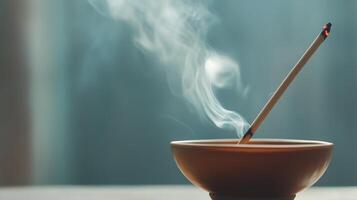 Incense stick burning in a ceramic holder with smoke wafting upwards in a serene setting photo