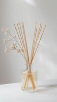 Decorative diffuser with reeds and dried flowers on a table in a minimalist setting photo