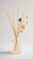 Dried flowers in a clear glass vase with natural reed sticks for home decor on a neutral background photo