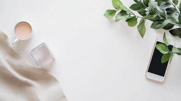 Cozy workspace with coffee cup, smartphone, and greenery on simple white table photo