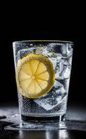 A glass filled with sparkling water and ice is adorned with a vibrant slice of lemon, creating a refreshing and visually appealing presentation photo