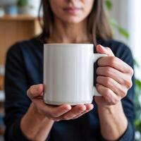 A person holds out a large white mug with both hands, the focus on the mug rather than the face photo