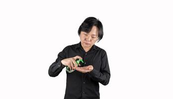 Asian man hand holds a gel alcohol pump bottle and ready to pushes on it. It's an isolated object on the white clear screen in studio light. photo