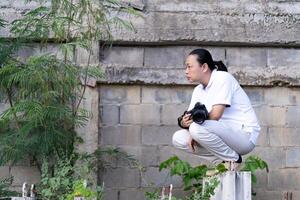 Asian Professional cameraman sits and thinks about 5how to create a creativity photo in the construction area background and environment.