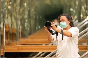 Photographer using camera to taking Self Portrait in 3the mirror.Photographer with a black SLR camera. photo