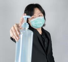 Asian mand holds a big blue gel alcohol pump bottle 1in front of him. An isolated man and object on the white clear screen in studio light. photo
