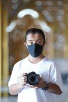 A man wearing black mask is shooting photo through a viewfinder camera with the right eye.33