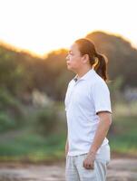 Asian Man long hair stands and relax on the dry field in golden twilight time.3 photo