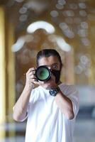 A man wearing black mask is shooting photo through a viewfinder camera with the right eye.2
