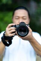 Asian man holds the Medium Format Camera in his 3hand and focus to shoot in front of him. photo