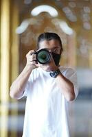 A man wearing black mask is shooting photo through a viewfinder camera with the right eye.3