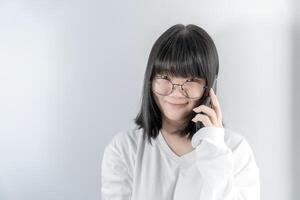 Isolated Pretty Asian glasses woman talks and speaks in the line with her mobile phone on white background in studio light.7 photo