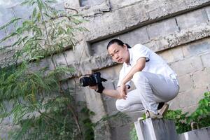 Asian Professional cameraman sits and thinks about 1how to create a creativity photo in the construction area background and environment.