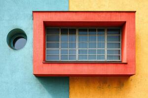 vibrant Bauhaus inspired facade with geometric shapes, featuring red rectangular window frame, circular detail, and bold color photo