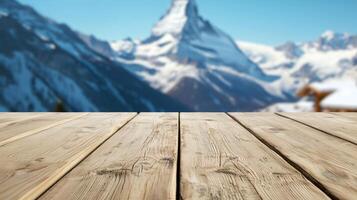 A Rustic wooden table with blurred view of snowy mountain peak and alpine architecture, crisp morning light enhances cool tones photo