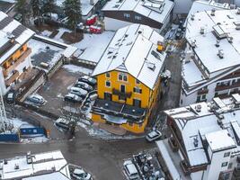 aéreo ver de cortina, Italia, presentando un brillante amarillo edificio con un inclinado techo y arqueado ventanas, rodeado por alpino arquitectura y Nevado tejados. foto
