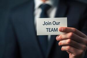 business man holding paper card with join our team text. photo