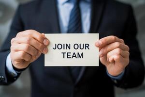a business man holding paper card with join our team text. photo
