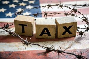 tax on wooden block in Tariffs concept with United States of America Flag. photo
