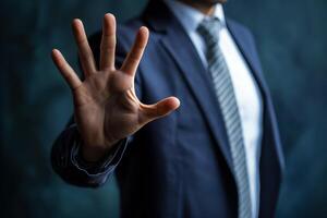 Businessman displays clear stop gesture in modern office. Confident hand signals halt to potential problems deals. Raised palm conveys firm decision warning. In formal setting. Blurred background. photo
