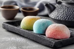 Colorful mochi dessert trio on black stone plate photo