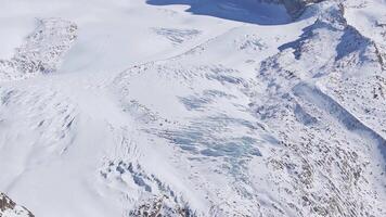 Sweeping aerial view of snow covered peaks, ridges, and glacial terrain at Zermatt ski resort, with the Matterhorn mountain in the background. video