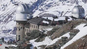 Aerial view of Gornergrat Observatory with twin domes, surrounded by snow covered peaks and the Matterhorn, with gradual camera movement. video