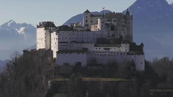 Aerial view of Hohensalzburg Fortress in Salzburg, Austria, with the Alps in the background. The camera moves smoothly, capturing winter scenery. video