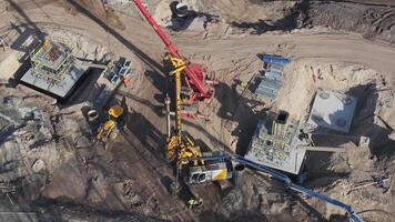 Workers and machinery operate on a concrete structure with scaffolding, dirt roads, and excavation areas, showcasing ongoing bridge construction. video