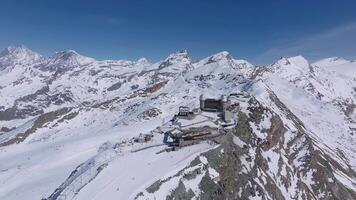 Aerial view of Zermatt ski resort with Matterhorn peak and Gornergrat observatory. The camera moves over snow covered mountains and glaciers under clear skies. video