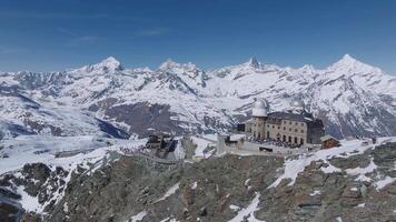 Smooth aerial sweep over Zermatt ski resort, showcasing the Matterhorn peak, snow covered alpine terrain, and Gornergrat observatory under clear skies. video
