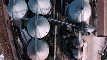 Metal silos on field aerial view. Large containers for storing and processing grains. Silver grain elevators in farmland. Storage tank view from above. Silo with grain. 13 video