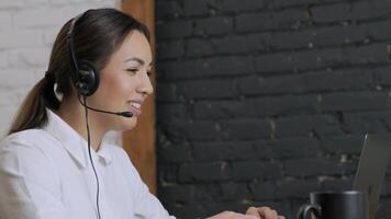 Customer service representative in headset communicating via laptop, engaged in support or virtual assistance in modern office setting. 7 video
