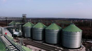 Large containers for storing and processing grains. Silver grain elevators in farmland. Storage tank view from above. Silo with grain. 8 video