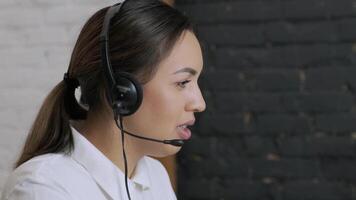 Customer service representative in headset communicating via laptop, engaged in support or virtual assistance in modern office setting. 6 video