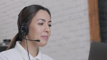 Customer service representative in headset communicating via laptop, engaged in support or virtual assistance in modern office setting. 3 video
