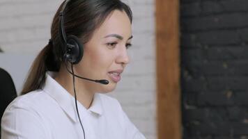 Customer service representative in headset communicating via laptop, engaged in support or virtual assistance in modern office setting. 22 video