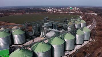 Metal silos on field aerial view. Large containers for storing and processing grains. Silver grain elevators in farmland. Storage tank view from above. Silo with grain. 10 video