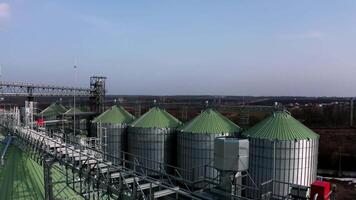 Metal silos on field aerial view. Large containers for storing and processing grains. Silver grain elevators in farmland. Storage tank view from above. Silo with grain. 7 video