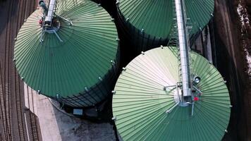 Metal silos on field aerial view. Large containers for storing and processing grains. Silver grain elevators in farmland. Storage tank view from above. Silo with grain. 14 video