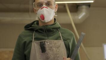 Portrait of worker carpenter with respirator and glasses in workshop, holds the ruler 2 video