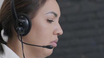 Customer service representative in headset communicating via laptop, engaged in support or virtual assistance in modern office setting. 4 video