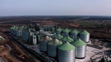Metal silos on field aerial view. Large containers for storing and processing grains. Silver grain elevators in farmland. Storage tank view from above. Silo with grain. 11 video