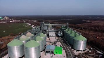 Metal silos on field aerial view. Large containers for storing and processing grains. Silver grain elevators in farmland. Storage tank view from above. Silo with grain. 12 video