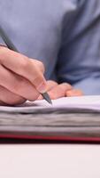 vertical Office worker writing notes on paper in a binder at night video