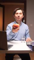 vertical Office worker eating apple and working on laptop at desk video