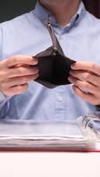 vertical Businessman showing empty wallet at office desk with documents and laptop video
