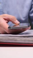 vertical Businessman using smartphone and consulting documents in binder video