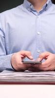 vertical Real estate agent using smartphone in office with stack of documents and files video
