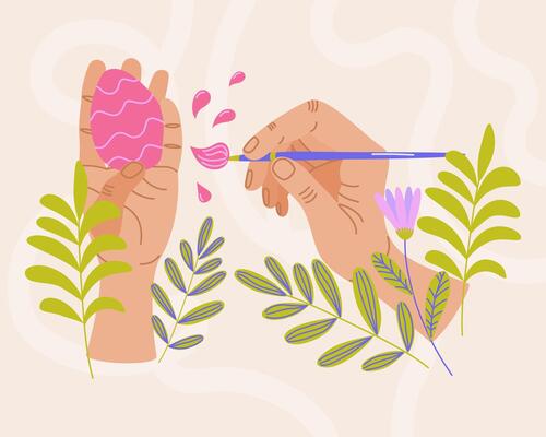 Hands painting pink Easter egg with brush surrounded by green leaves and flowers on light background. Easter celebration and springtime holidays concept. For greeting card, invitation, banner.